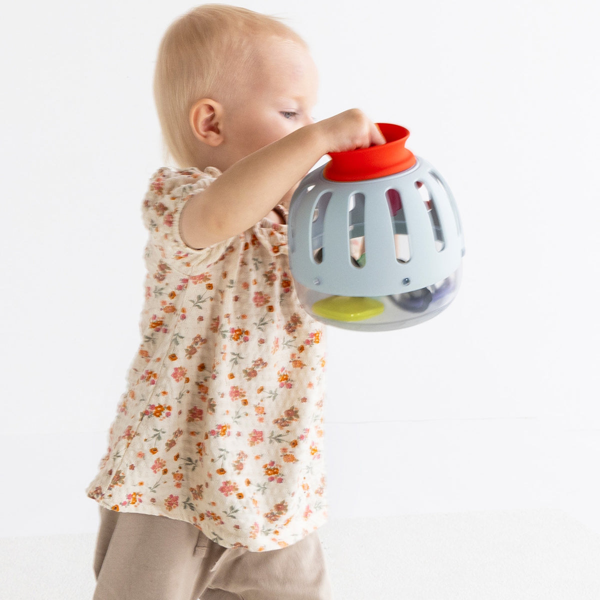 Side view of a toddler holding a light blue plastic toy curiosity lantern.