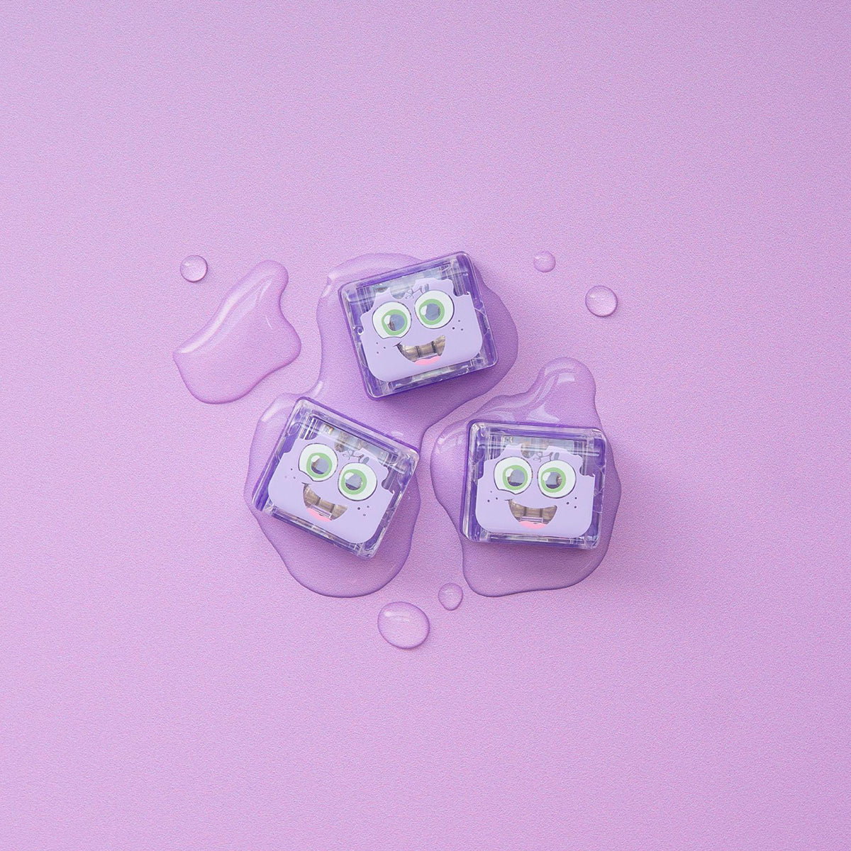Three purple Lumi Glo Pals light-up cubes on a lilac background with water droplets.