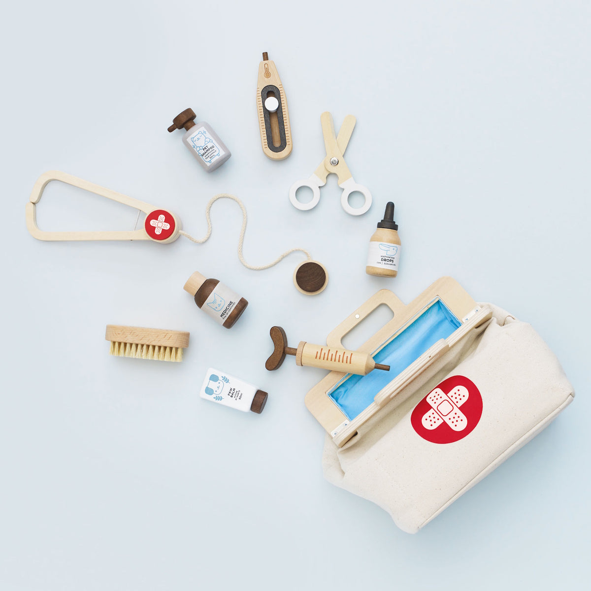 Wooden vet play set with stethoscope, syringe, and medical accessories around an open canvas bag.