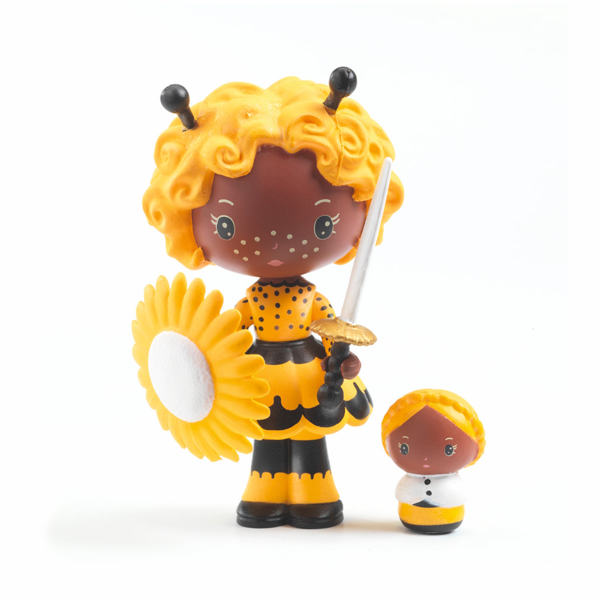 Toy figure of a girl with curly yellow hair, black antennas, and a yellow polka dot dress. She's holding a sunflower and a sword, standing next to a smaller figure.