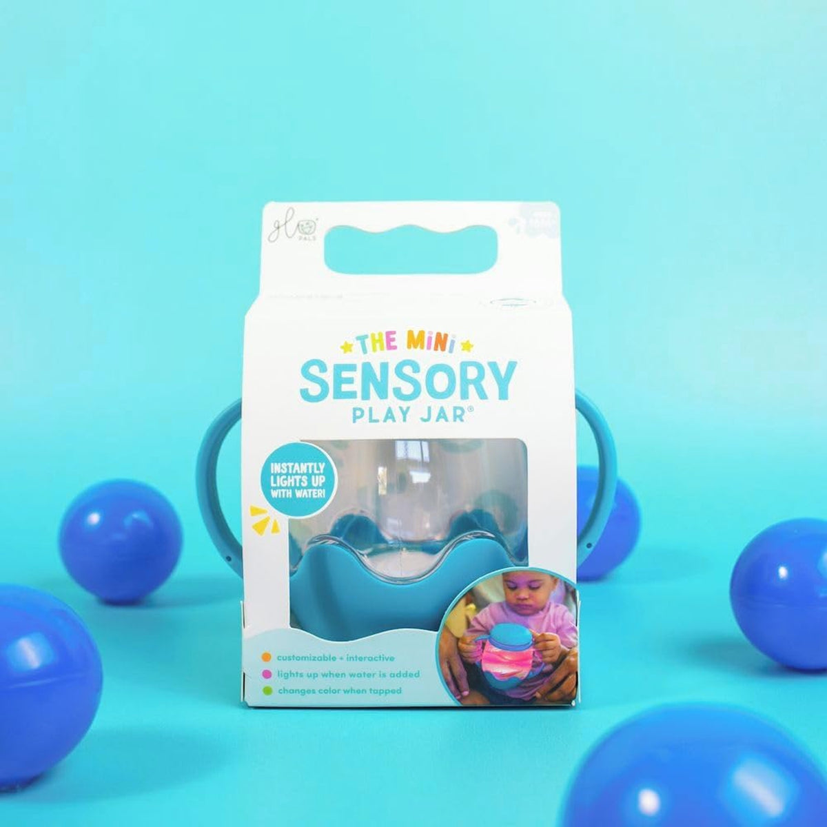 Glo Pals Mini Sensory Play Jar in blue box packaging surrounded by blue plastic balls.
