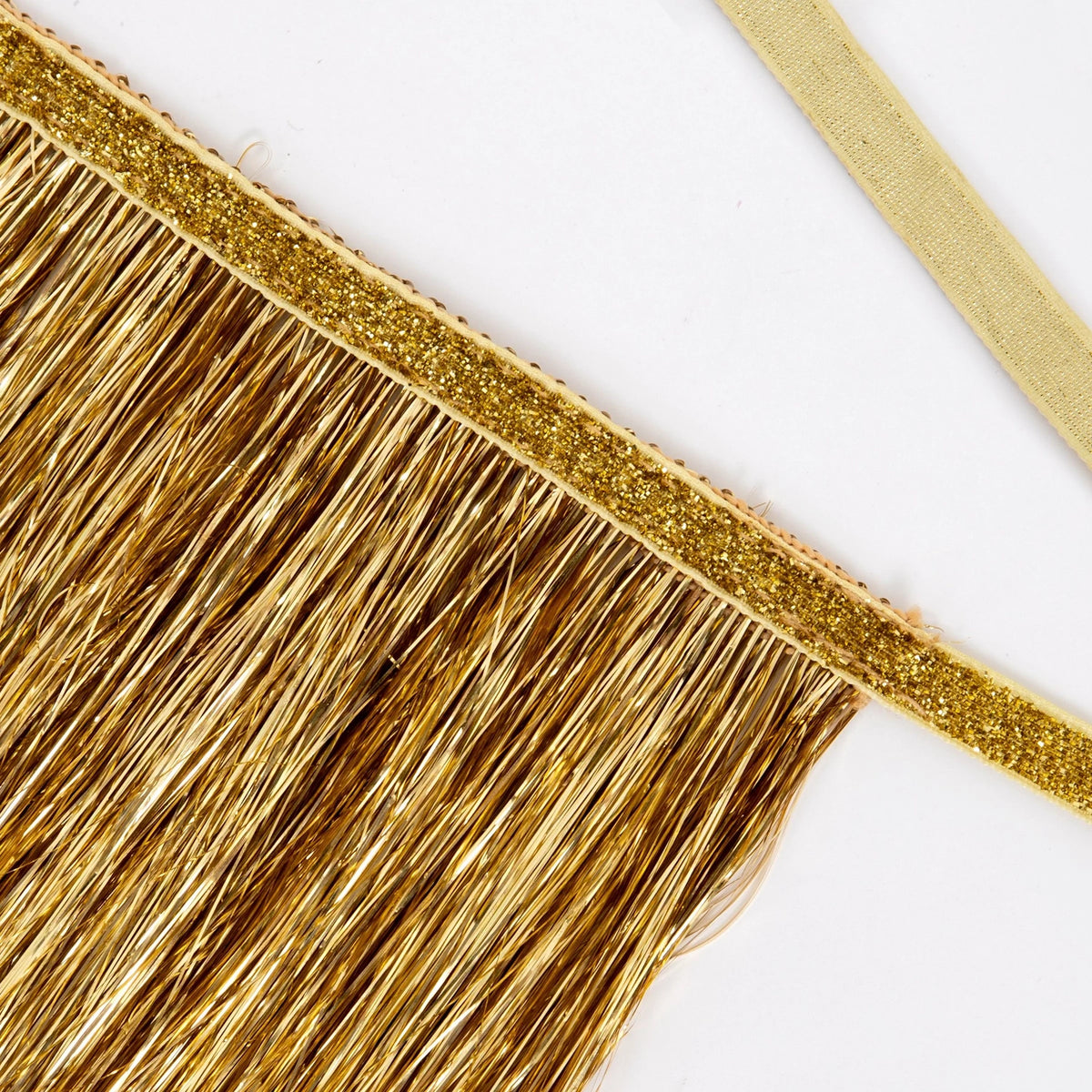 Close-up of metallic gold tinsel fringe with a glittery trim along the top border.