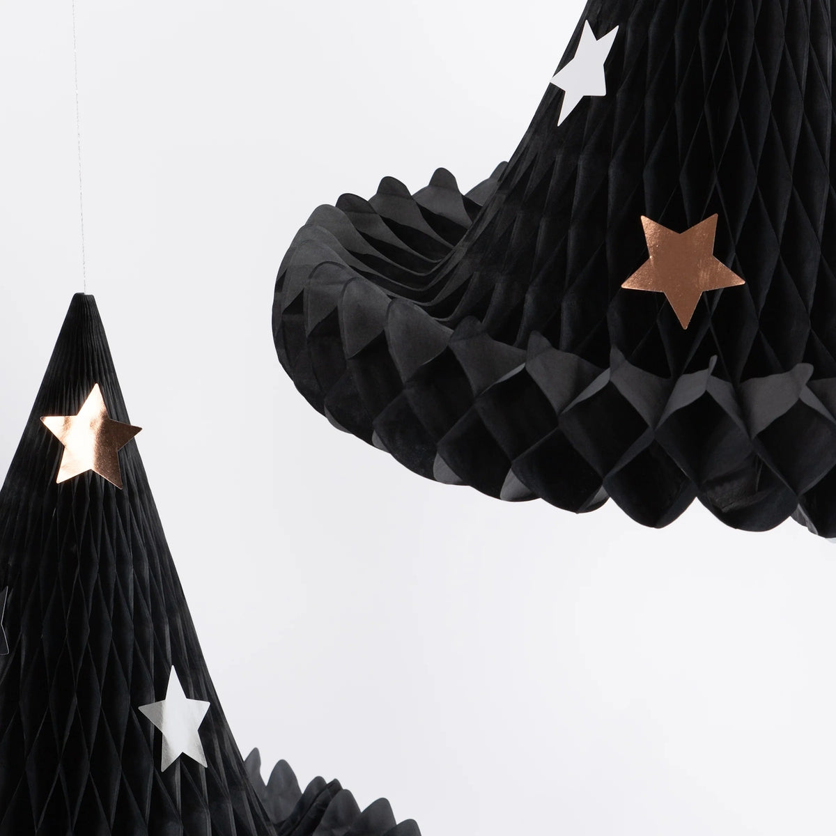 Close-up of black paper honeycomb witch hat decorations featuring silver and copper star details.
