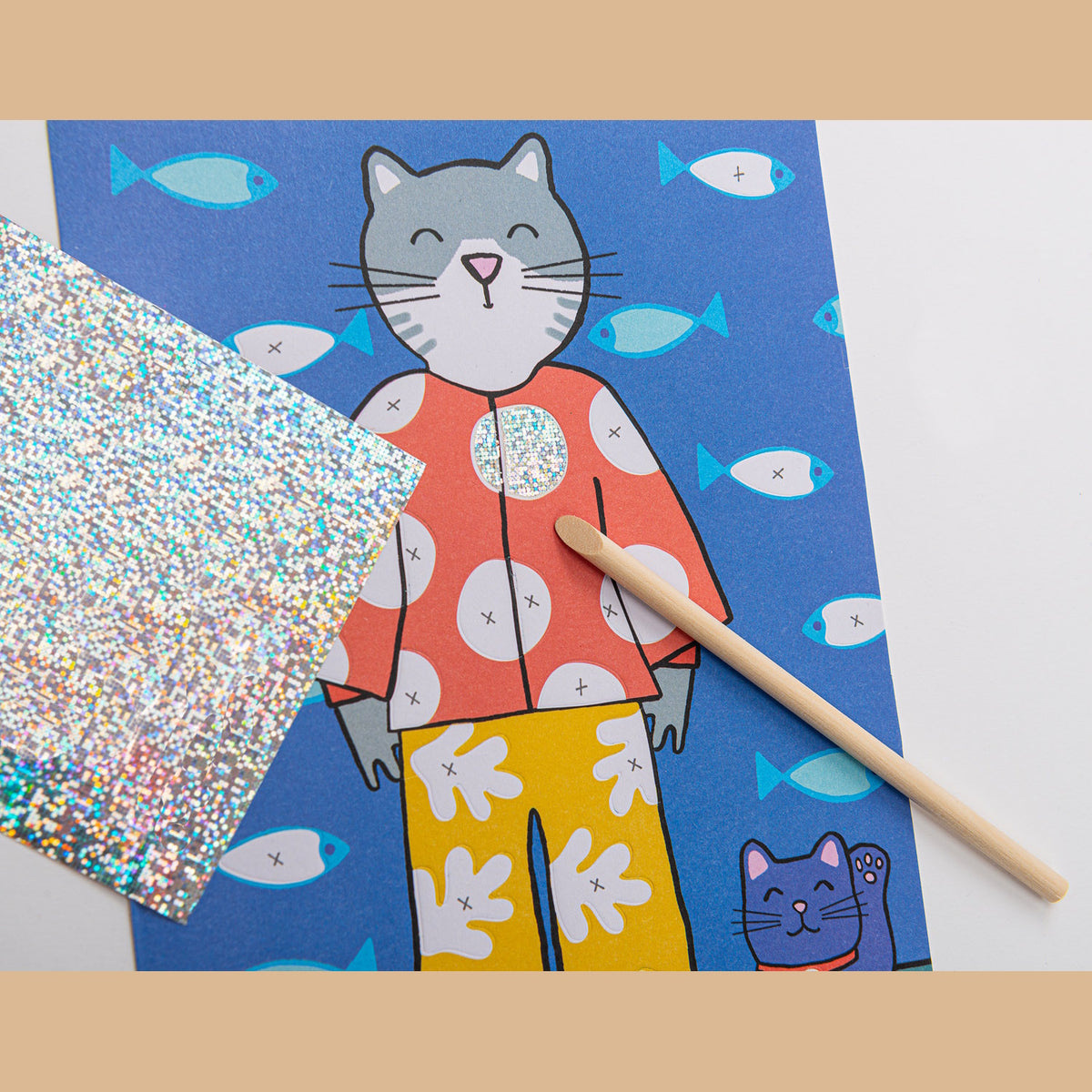 Cat foil art activity kit featuring a cat illustration being decorated with holographic glitter sheets and a wooden stylus.