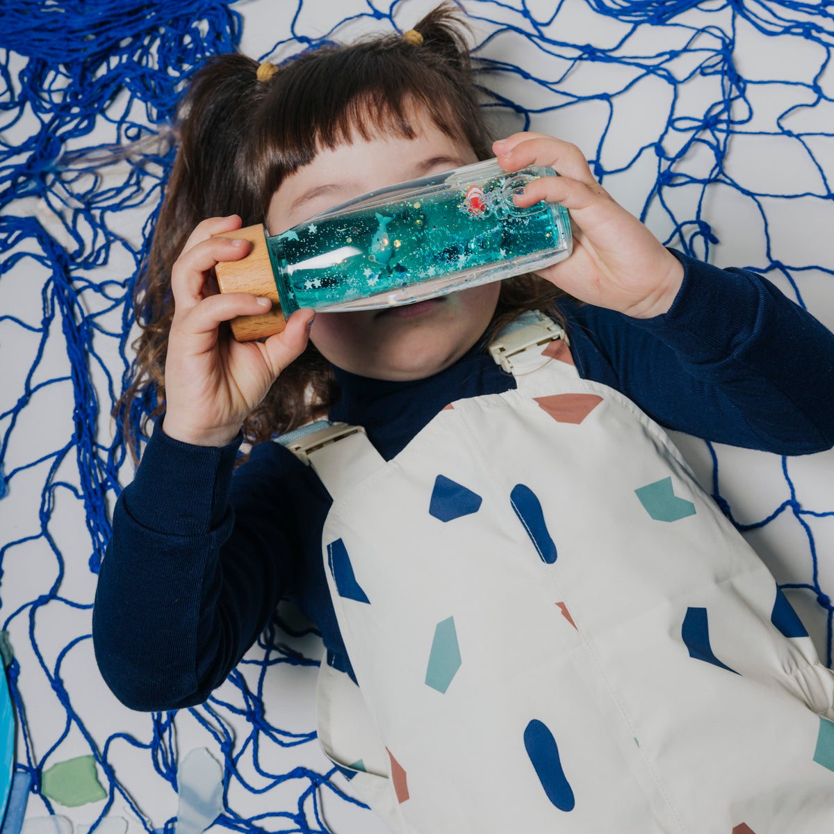 Girl holding a sensory bottle to look through it.