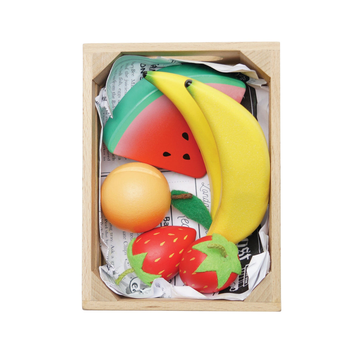 Top-down view of wooden play fruits packed in a crate lined with newspaper.