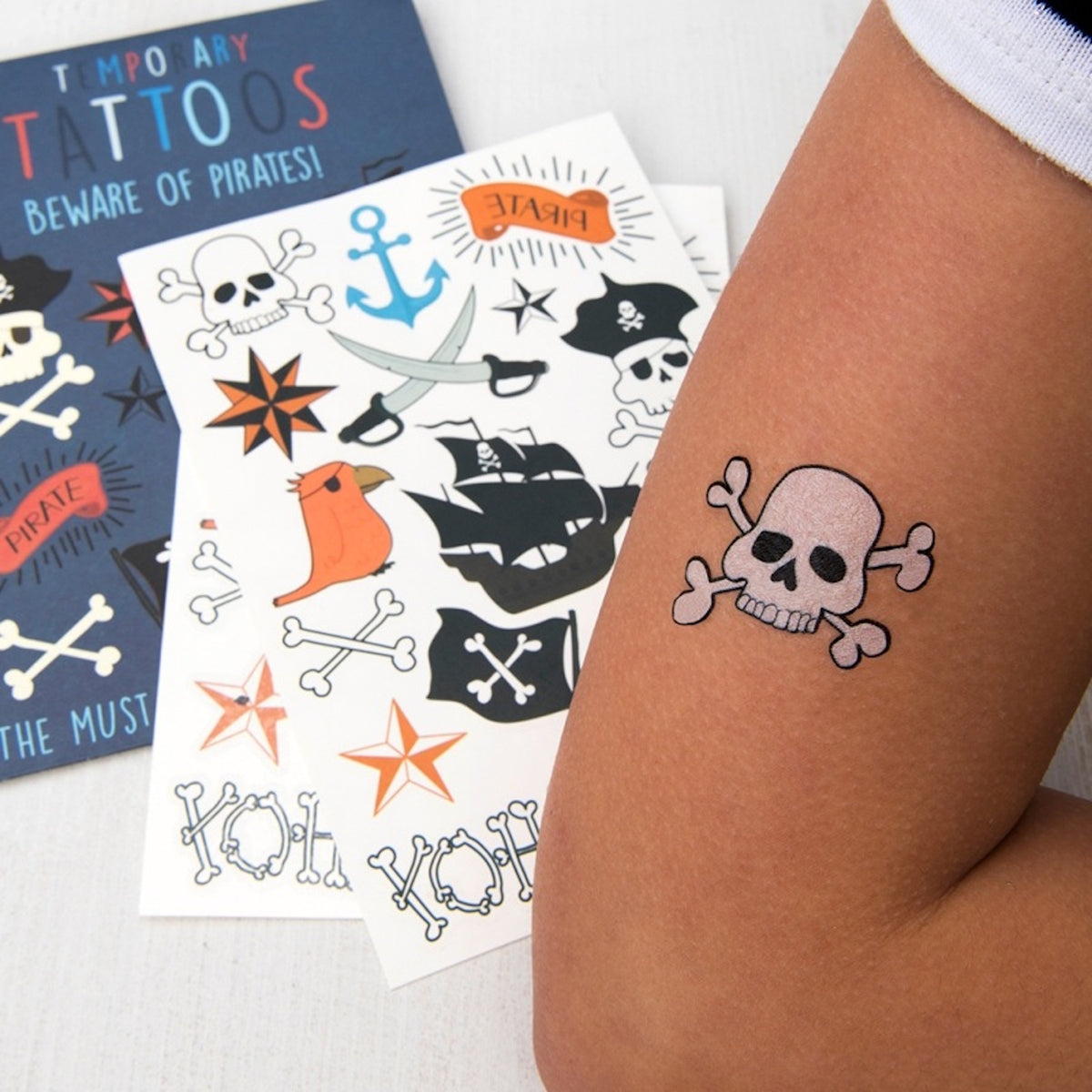 Child wearing a skull and crossbones temporary tattoo with pirate sheet pack in background.