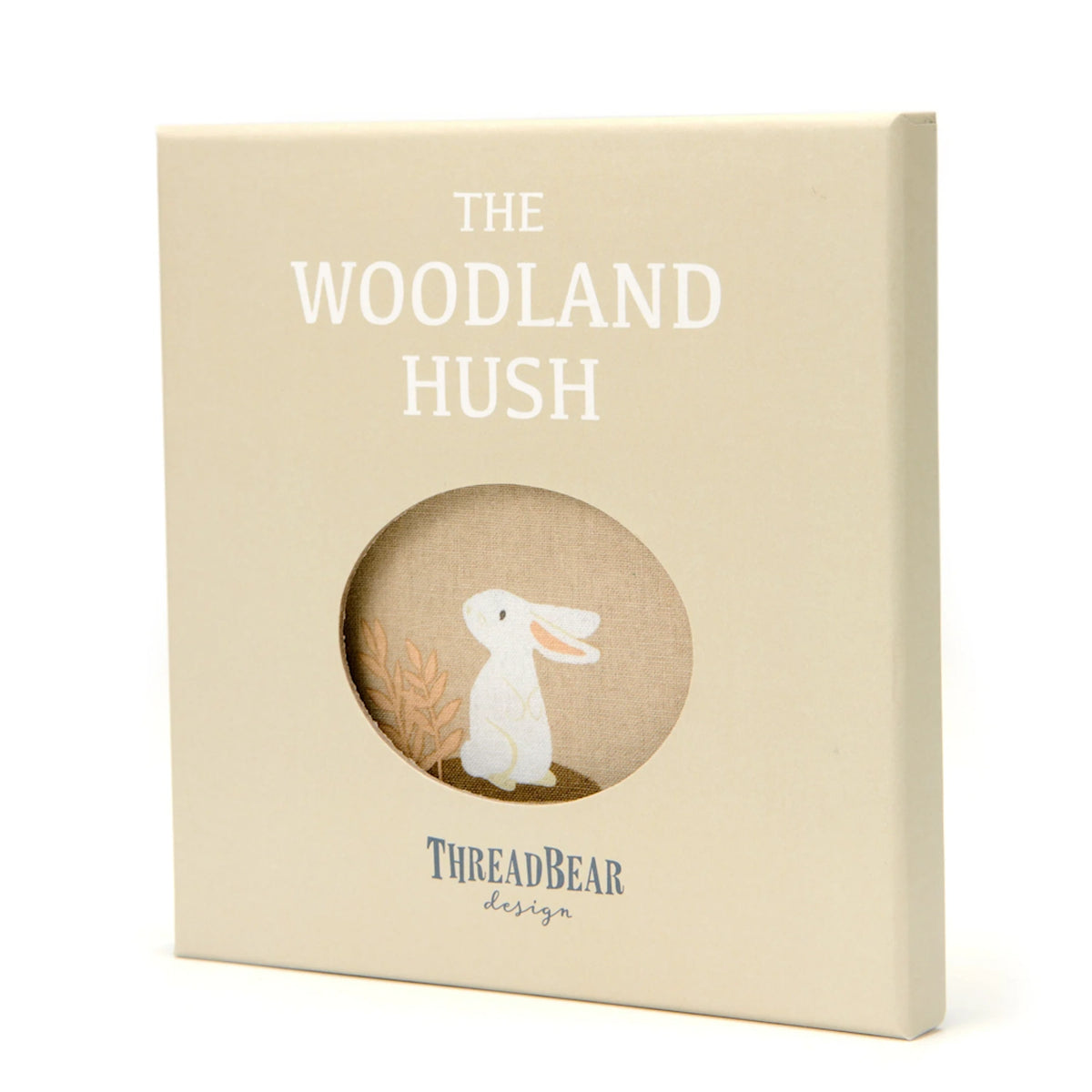 Square gift box titled "The Woodland Hush" with a circular cutout revealing a white rabbit illustration.