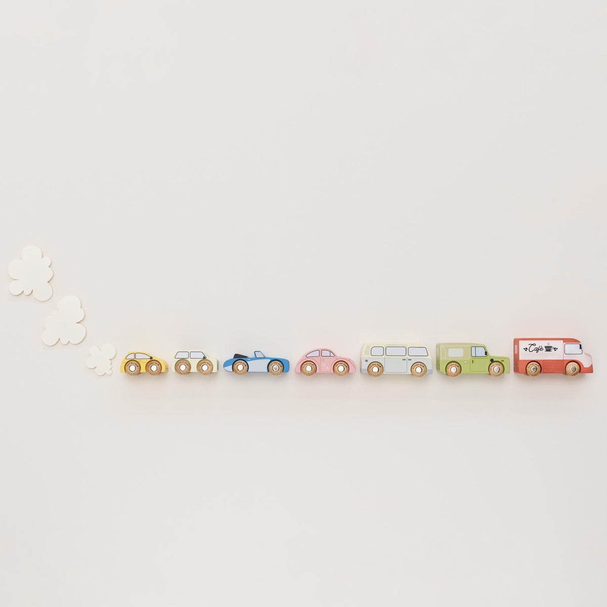 Seven vintage-style wooden toy cars lined up in a row with white felt exhaust clouds on a beige background.