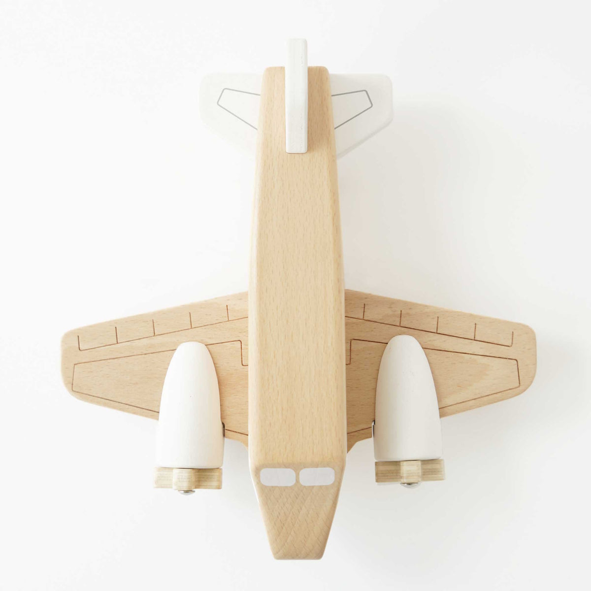 Top-down view of a natural wooden toy airplane with white painted engines and tail fin.