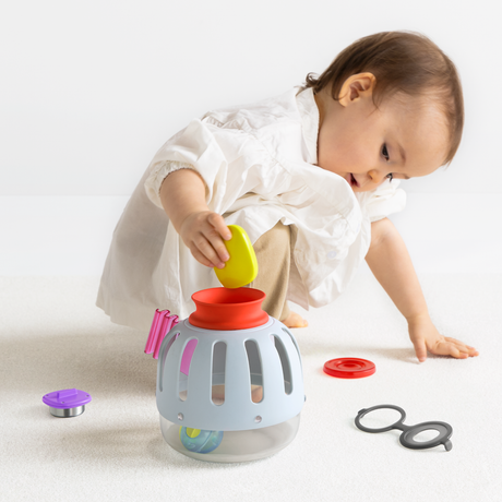 Side view of a toddler playing with a light blue plastic toy curiosity lantern and colorful pieces.