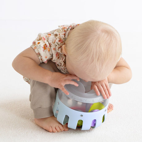 High-angle view of a toddler exploring an inverted light blue plastic toy curiosity lantern.