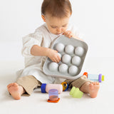 Front view of a toddler holding the light gray silicone Curiosity Nook toy.