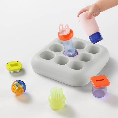 High-angle view of the light gray silicone 1curiosity Nook developmental toy with colorful insert pieces.
