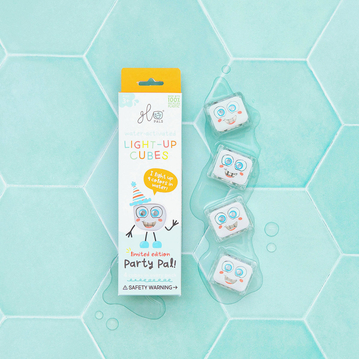 Glo Pals Party Pal light-up cubes with packaging displayed on a wet teal hexagonal tile surface."