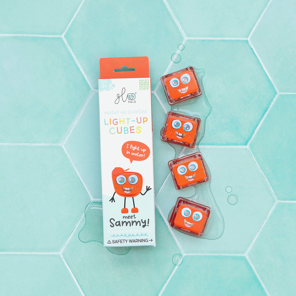 Glo Pals Sammy light-up cubes in packaging, placed on a blue tiled surface with water droplets.