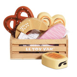Wooden crate filled with toy bakery items and pastries on a white background.