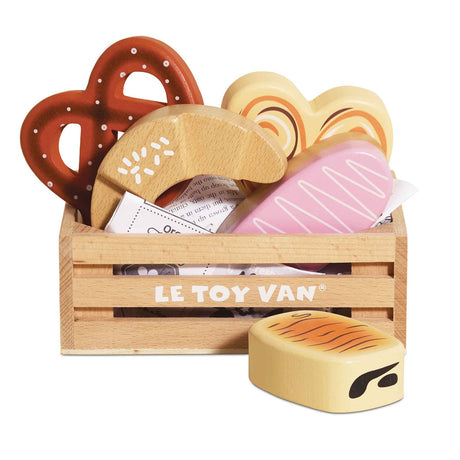 Wooden crate filled with toy bakery items and pastries on a white background.
