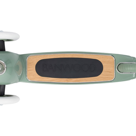 Top-down view of a sage green scooter deck with a wooden finish and black Banwood grip pad on a white background.