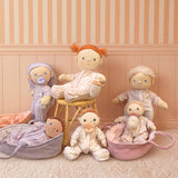 Collection of plush Dinkum dolls in patterned pajamas with toy bassinets and feeding accessories.