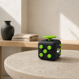 Front view of a black plastic multi-sensory fidget cube on a stone table.
