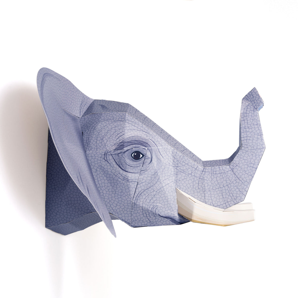 A paper sculpture of an elephant's head with a raised trunk, featuring geometric patterns and textures, set against a plain white background.
