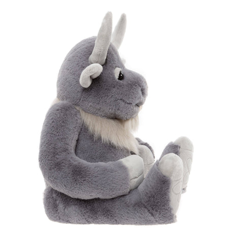 Side profile of a plush grey horned creature toy sitting down, showing curved horns and light fur beard.