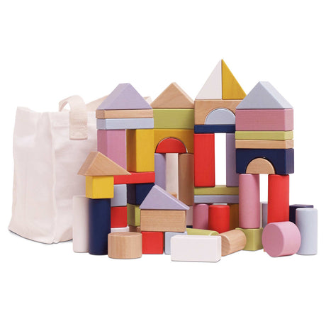 Colorful wooden building blocks stacked into castle shapes next to a white canvas storage bag.