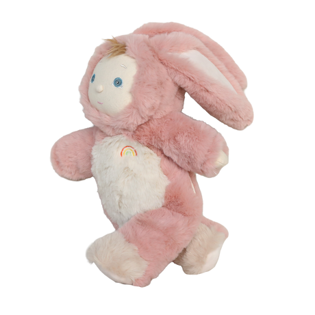 Side view of a plush baby doll in a fuzzy pink bunny suit with floppy ears and a rainbow emblem.