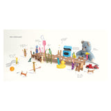 Book page showing crayons and toys gathered around a long cardboard table for a dinner party setup.