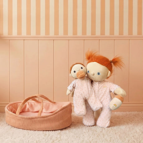 Two Dinkum Dolls in matching pink floral pajamas next to a pink corduroy doll moses basket.