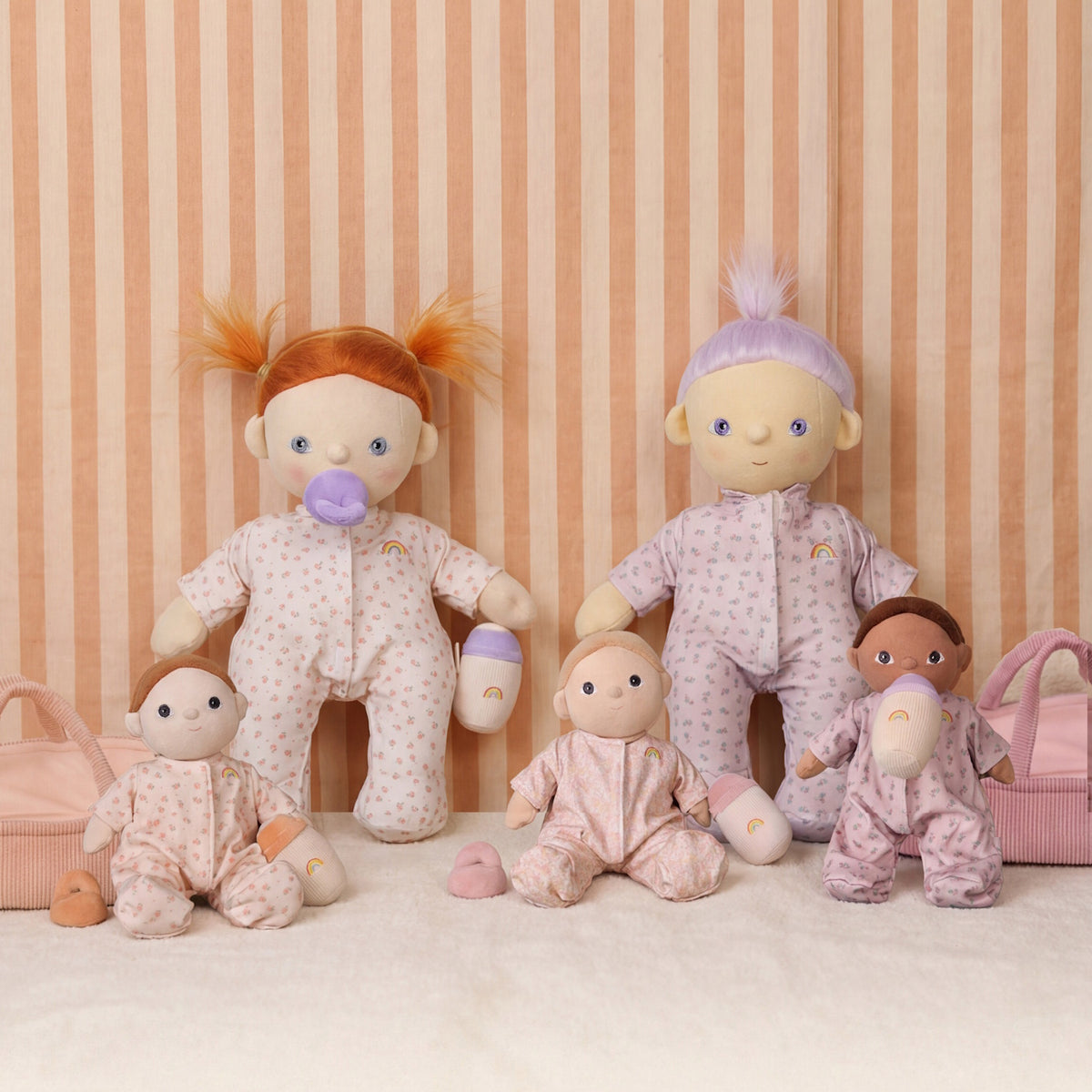Collection of Dinkum Dolls wearing matching floral Marlow pajamas with toy bottles.