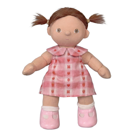 Dinkum doll with brown pigtails wearing a pink plaid rosette dress and pink shoes.