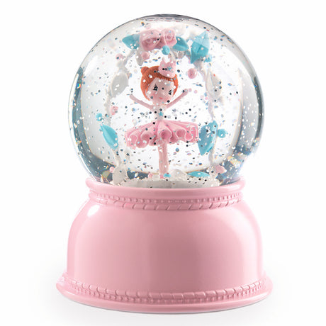 A pink snow globe featuring a cheerful ballerina in a tutu, surrounded by pastel flowers and confetti, creating a whimsical, playful atmosphere.
