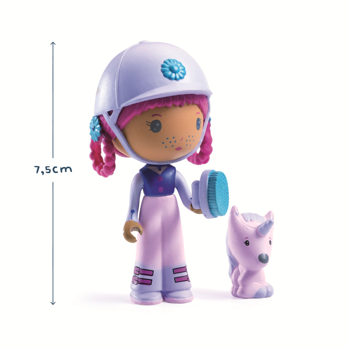 A doll with pink hair and a white helmet, holding a blue brush, stands beside a small purple unicorn. The doll wears a blue and pink outfit.