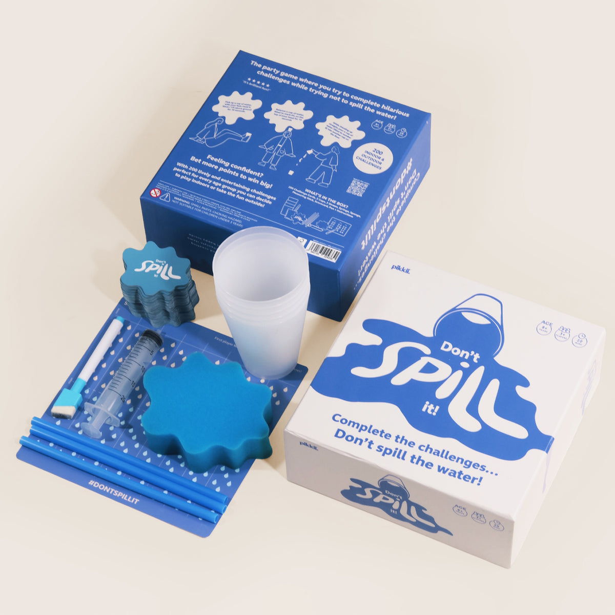 Don't Spill It! party game box displayed with plastic cups, blue sponge, straws, and cards.