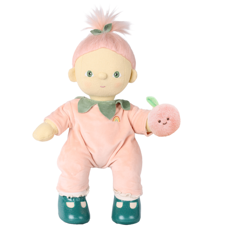 Olli Ella Cozy Dinkum Doll Piper Peach in a peach velour suit holding a plush peach rattle.