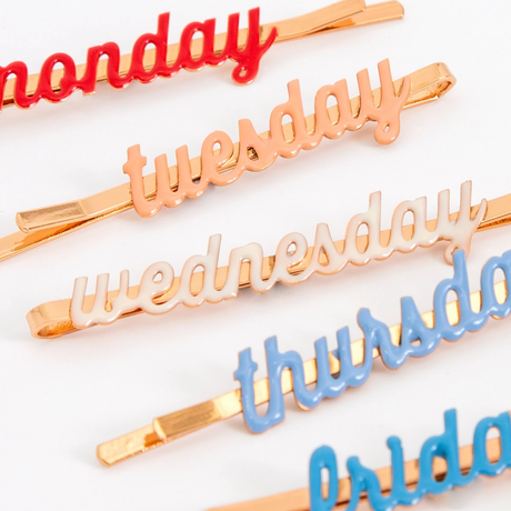 A set of enamel hair clips featuring the days of the week, perfect for adding a fun and functional touch to daily hairstyles.