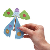 A hand holding a colorful paper fairy craft with green wings and a blue body.