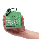 Hand holding "100 Fun Things to Do With a Stick" green activity card deck on a white background.
