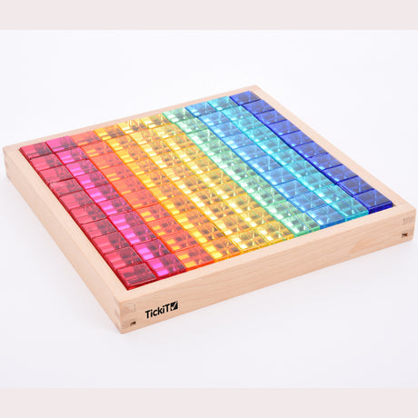 A square wooden tray with a mirrored base and colorful gem-like insets, designed to inspire sensory exploration, pattern making, and visual play.
