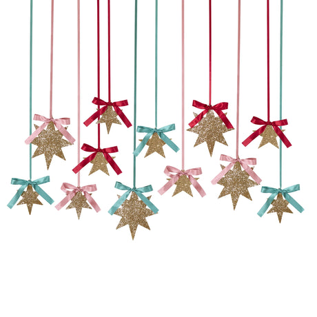Hanging gold glitter star decorations tied with colorful satin ribbons and bows.
