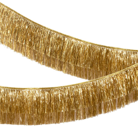 Side view of a double-layered metallic gold tinsel fringe garland swagged across a white background.