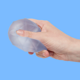 A hand squeezing a translucent, textured stress ball against a solid blue background. The image conveys a sense of tension release.