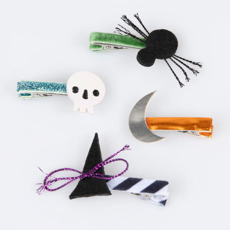 Four Halloween hair clips including a black spider, white skull, silver moon, and witch hat.