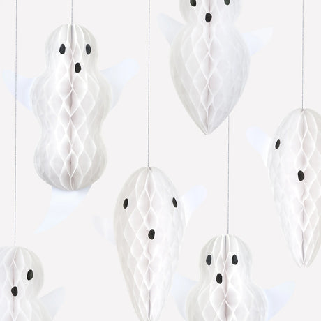 Close-up of white paper honeycomb hanging ghost decorations showcasing their textured detail and facial expressions.