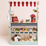 Front view of a wooden market stall play set with a red striped awning, register, and play food.