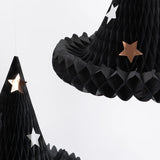 Close-up of black paper honeycomb witch hat decorations featuring silver and copper star details.