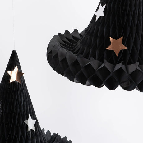 Close-up of black paper honeycomb witch hat decorations featuring silver and copper star details.