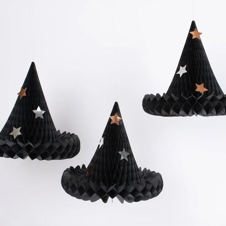Three black honeycomb paper witch hat decorations adorned with metallic star accents hanging against a white backdrop.